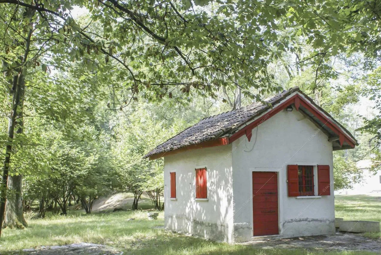 Dépendance bianca con porta e finestre rosse immersa nel parco