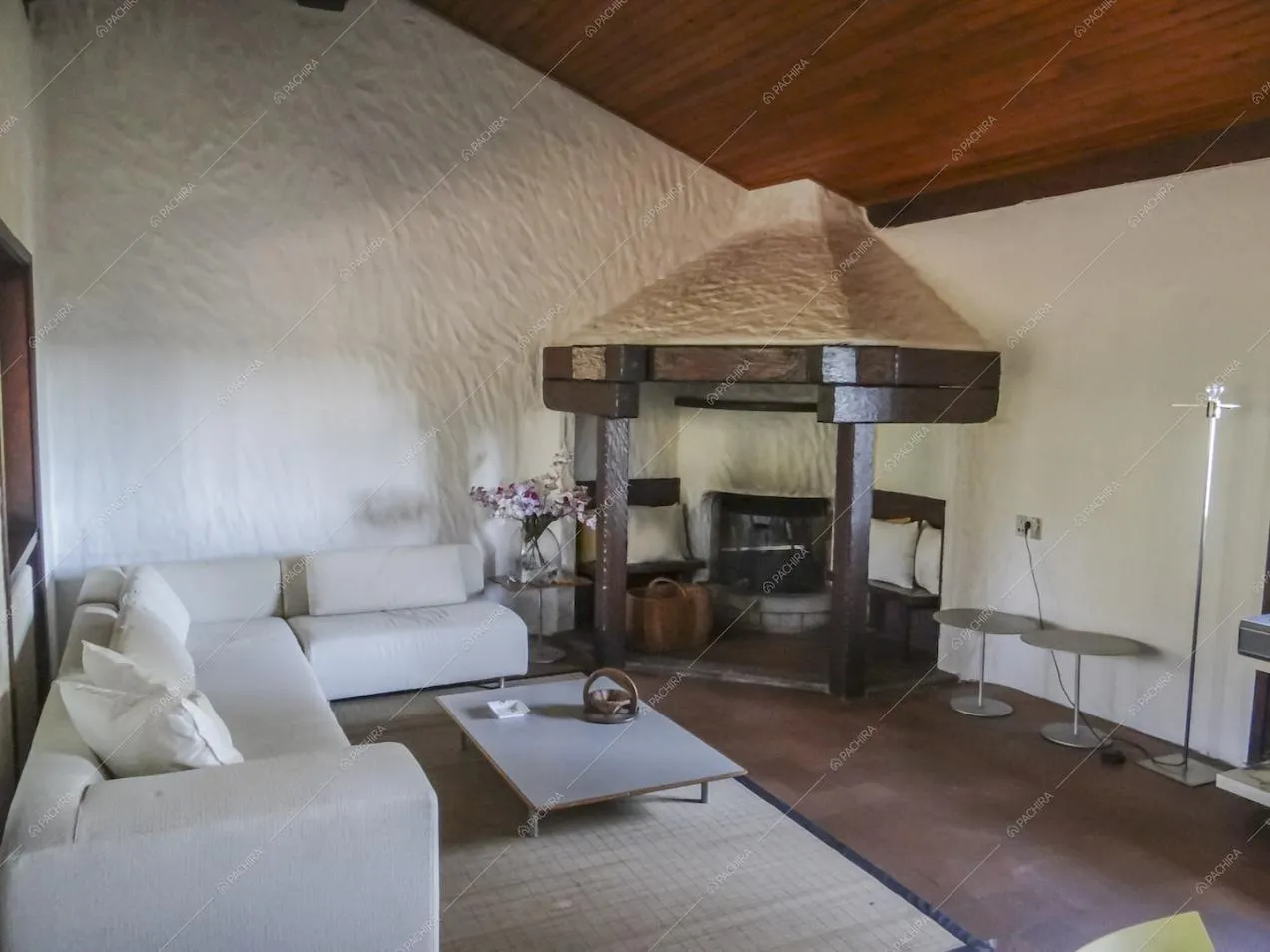 Salotto con camino, divano bianco angolare e soffitto in legno a vista