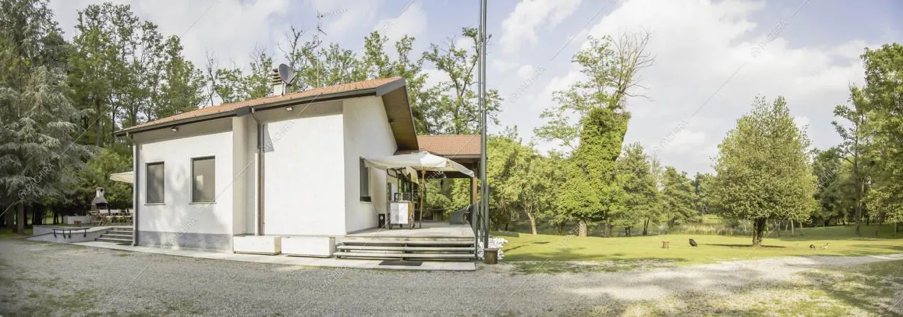 Esterni bianchi della location con veranda, forno in pietra e vista sul parco