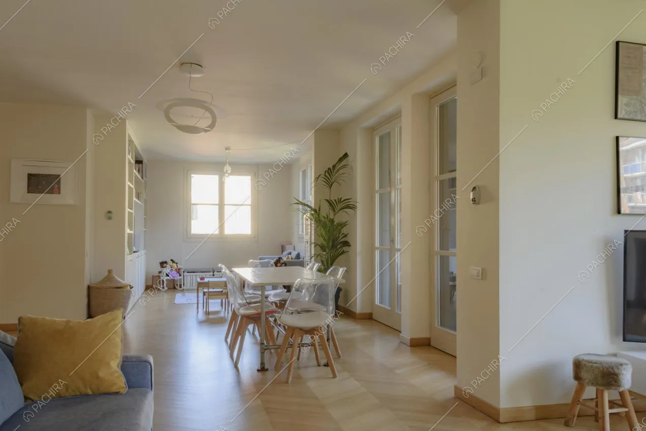 Lampada di design appesa al soffitto, tavolo con sedie e piccolo sgabello in pelliccia