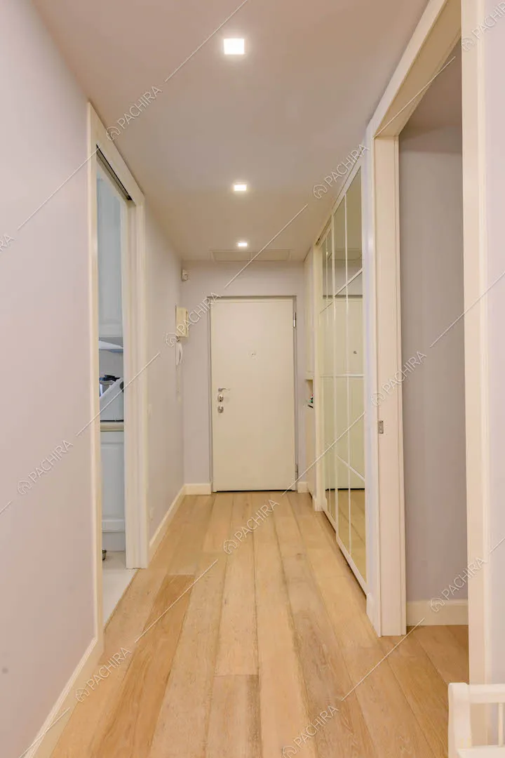 Corridoio con pavimento in parquet e vista su porta d'ingresso e cucina