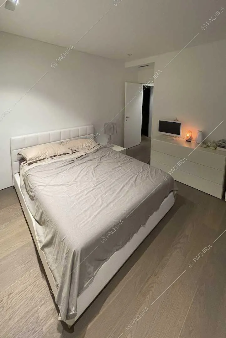 Letto matrimoniale in stanza dalle pareti bianche e con pavimento in parquet