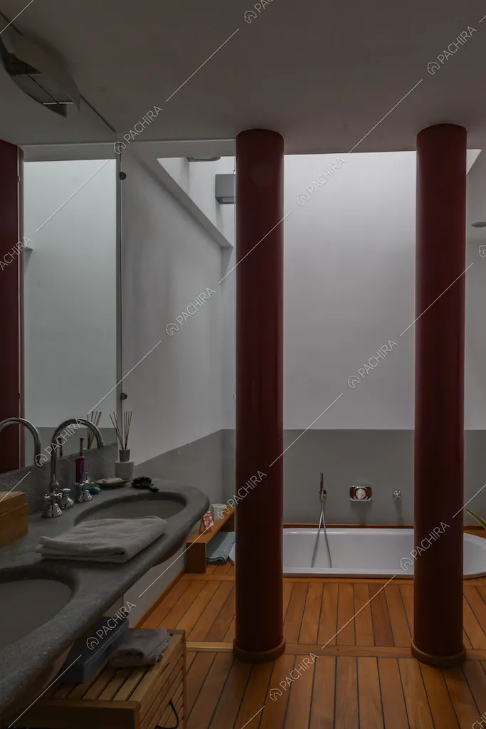 Bagno con pavimento in parquet, colonne rosse e vasca
