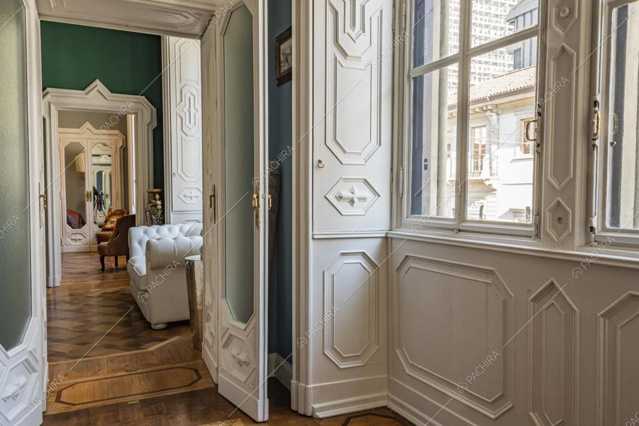 Infissi d'epoca intarsiati, parquet e poltrona bianca trapuntata