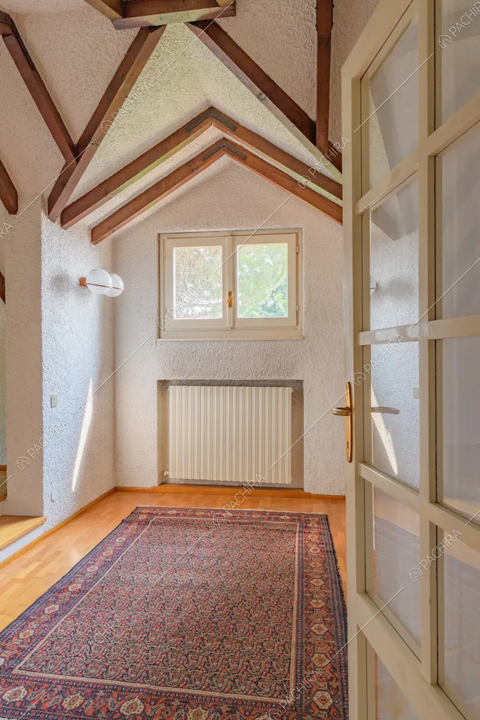 Travi in legno a vista sul soffitto della camera con pavimento in parquet