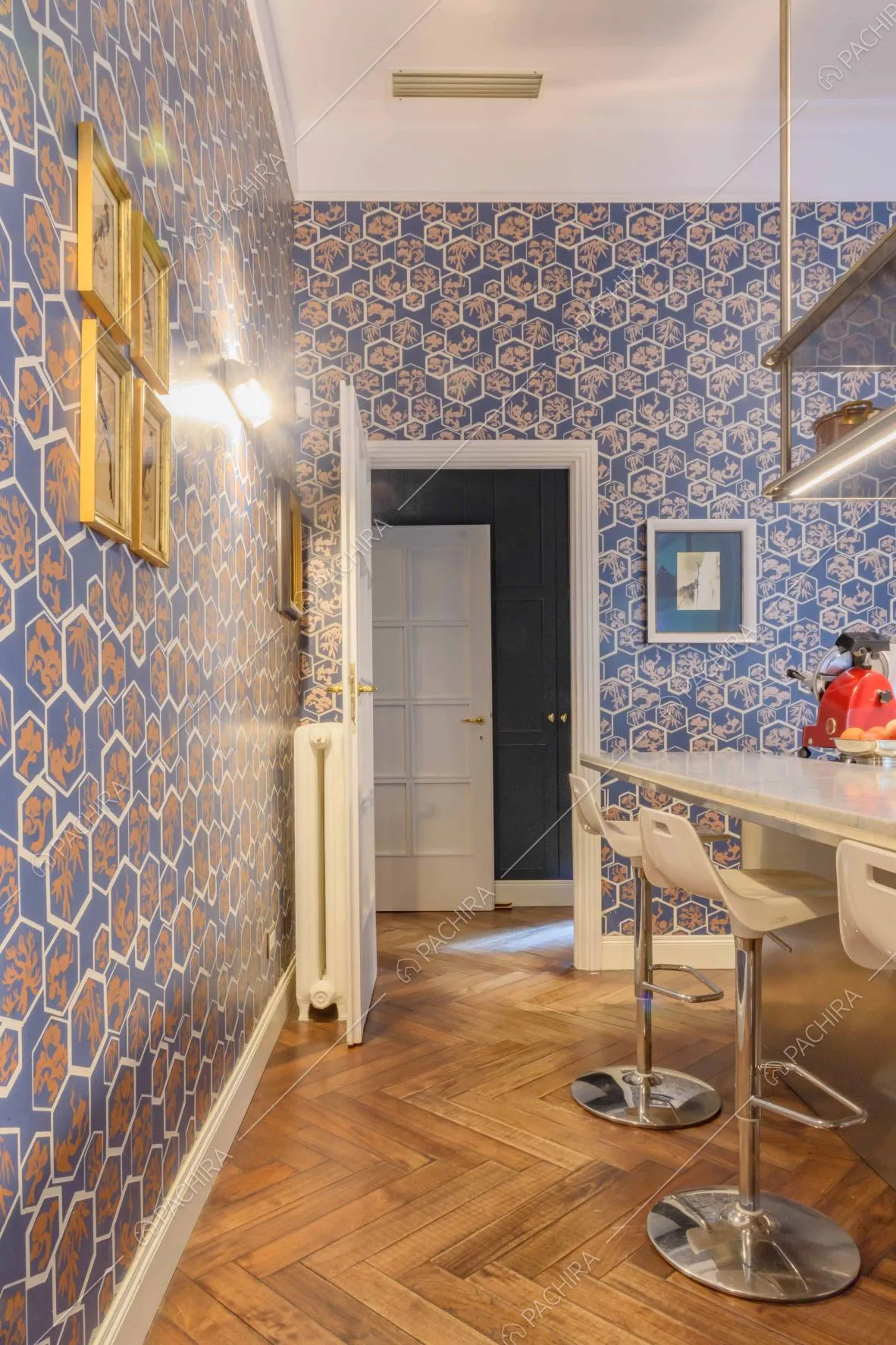 Cucina con carta da parati, pavimento in parquet a spina di pesce e isola con sgabelli