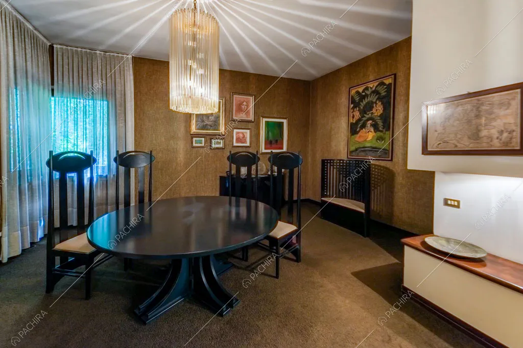 Pavimento in moquette nella zona living con tavolo nero rotondo e sedie di design