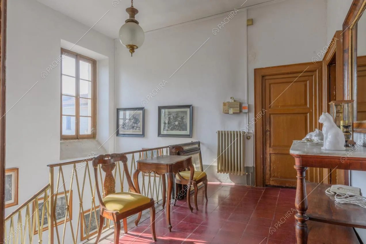 Pianerottolo con pavimento in piastrelle rosse, pareti bianche e porta in legno con boiserie
