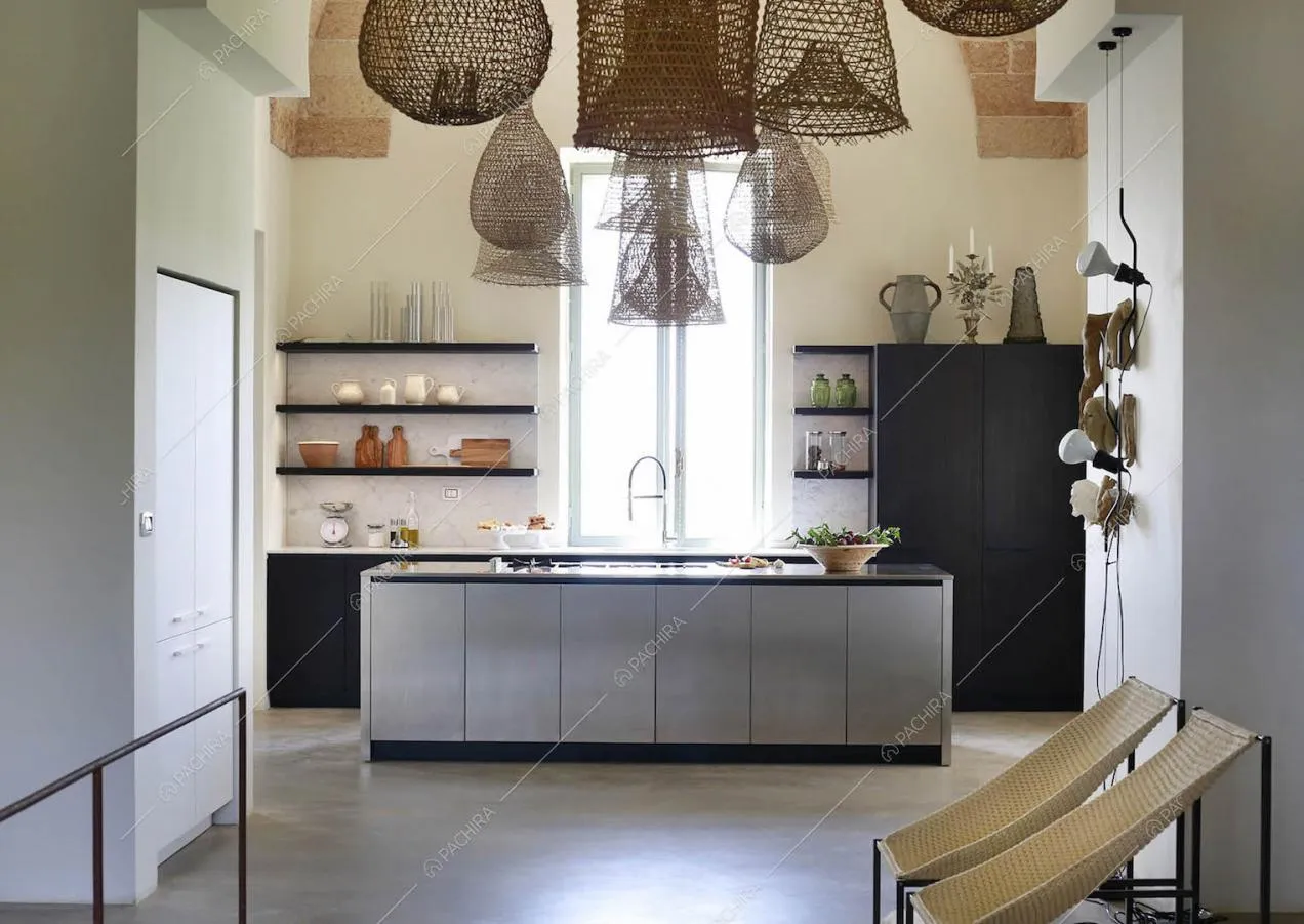 Cucina a vista con isola, lampadari in vimini e pavimento in cemento lisciato