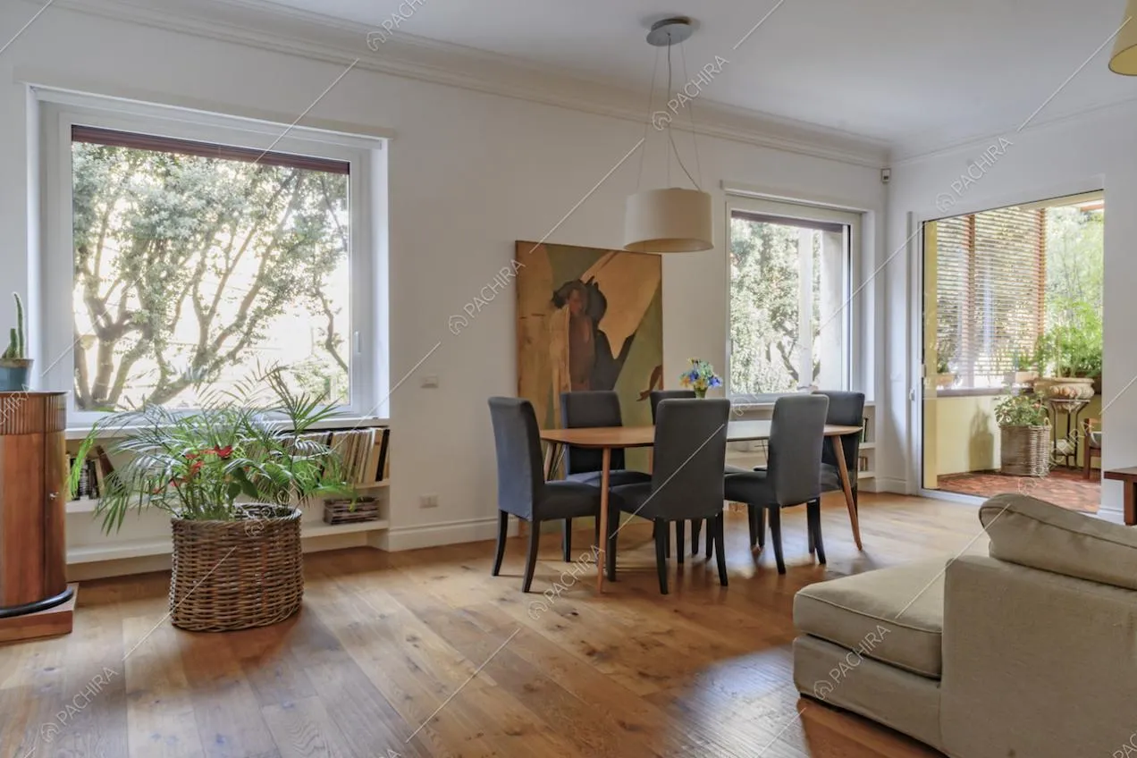 Salotto dalle pareti bianche con boiserie, vetrate e accesso alla terrazza