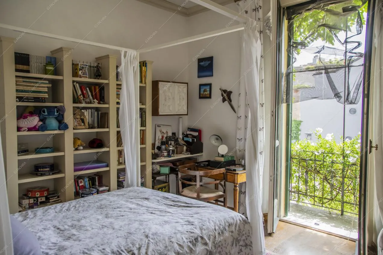 Luminosa camera da letto con struttura a baldacchino, pavimento in parquet e porta-finestra