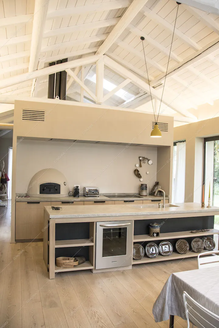 Cucina a vista completa di elettrodomestici sotto a travi bianche