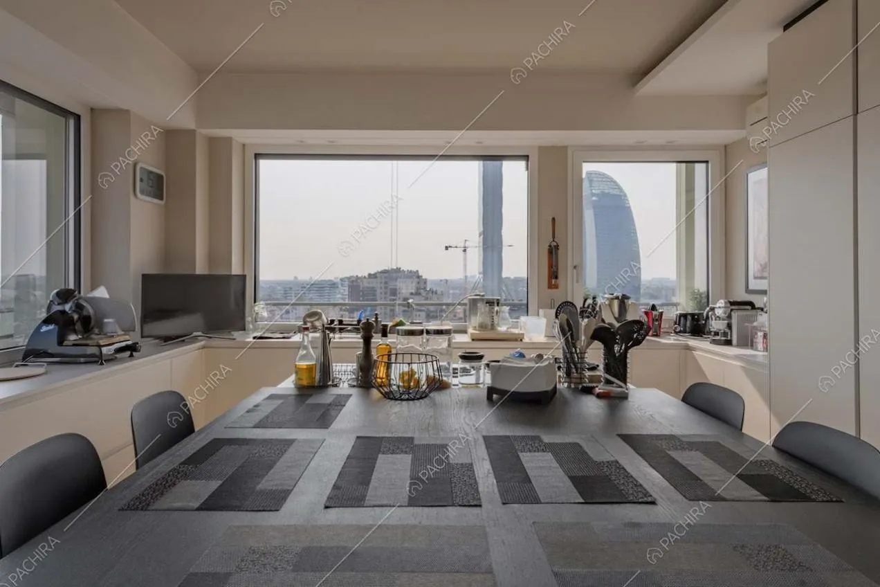 Cucina con isola e tavolo accostato e vetrate con vista sullo skyline