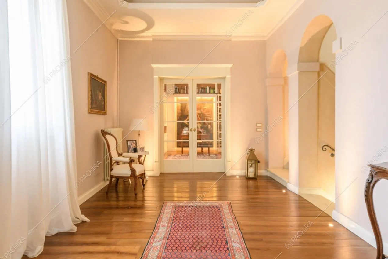 Luminoso corridoio con pavimento in parquet e porta a vetri per accedere allo studio