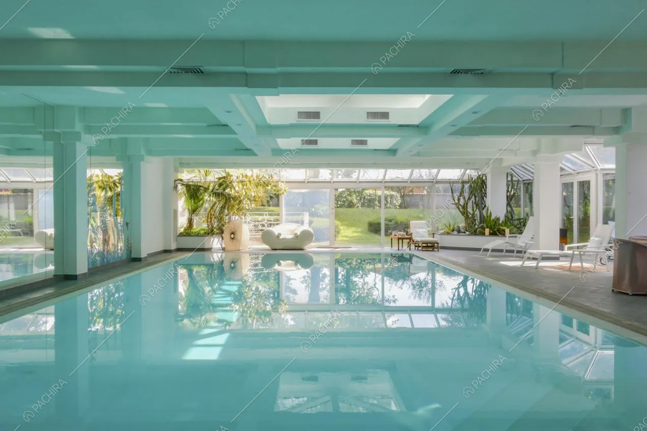 Piscina al chiuso con vista sul giardino tramite la ampie vetrate