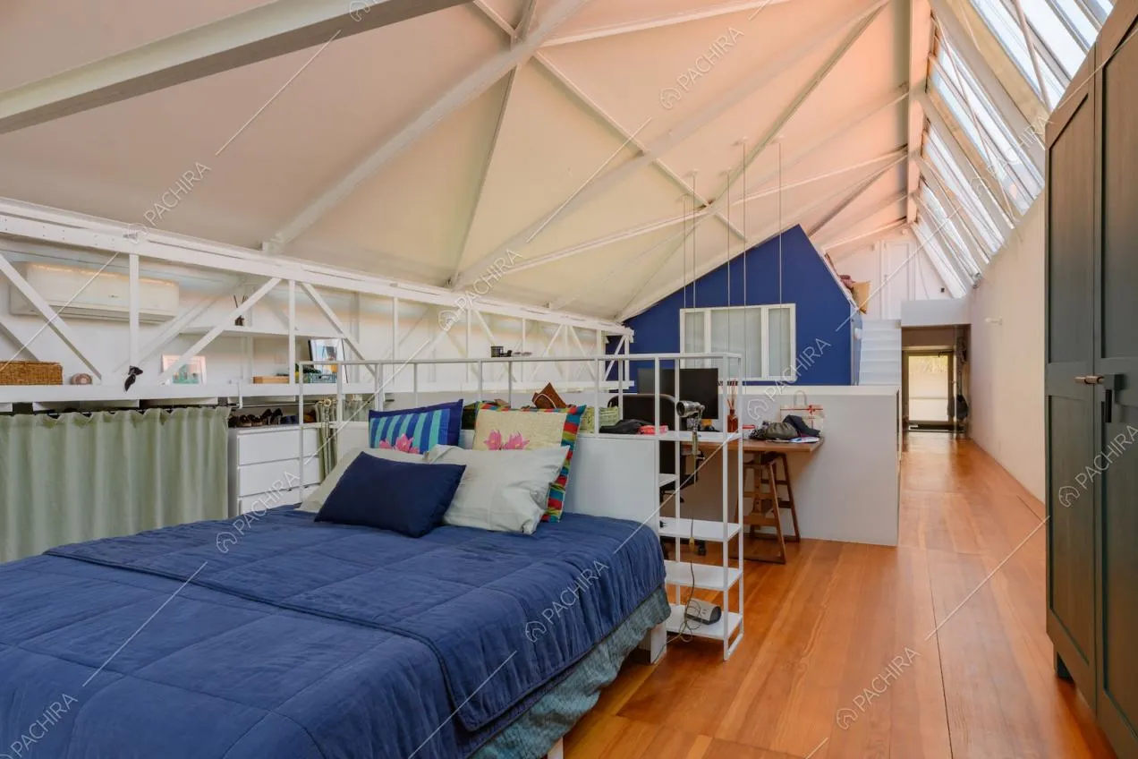 Camera da letto matrimoniale con pavimento in parquet, lucernari e travi a vista