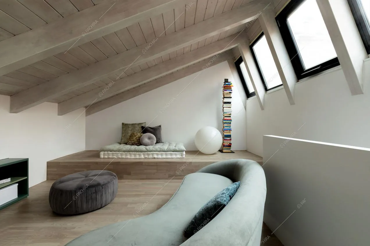 Divano nella camera da letto con lucernari e soffitto con travi in legno a vista