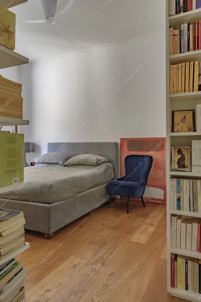 Vista sulla camera da letto matrimoniale con librerie, pavimento in parquet e pareti bianche
