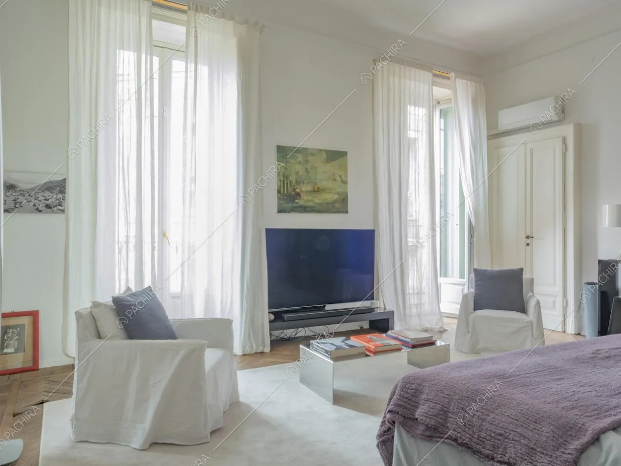 Grandi finestre con tende leggere bianche e porte d'epoca nella camera da letto