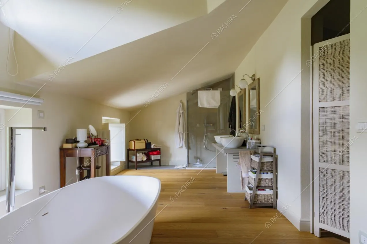 Bagno con vasca e box doccia nella mansarda con pavimento in parquet