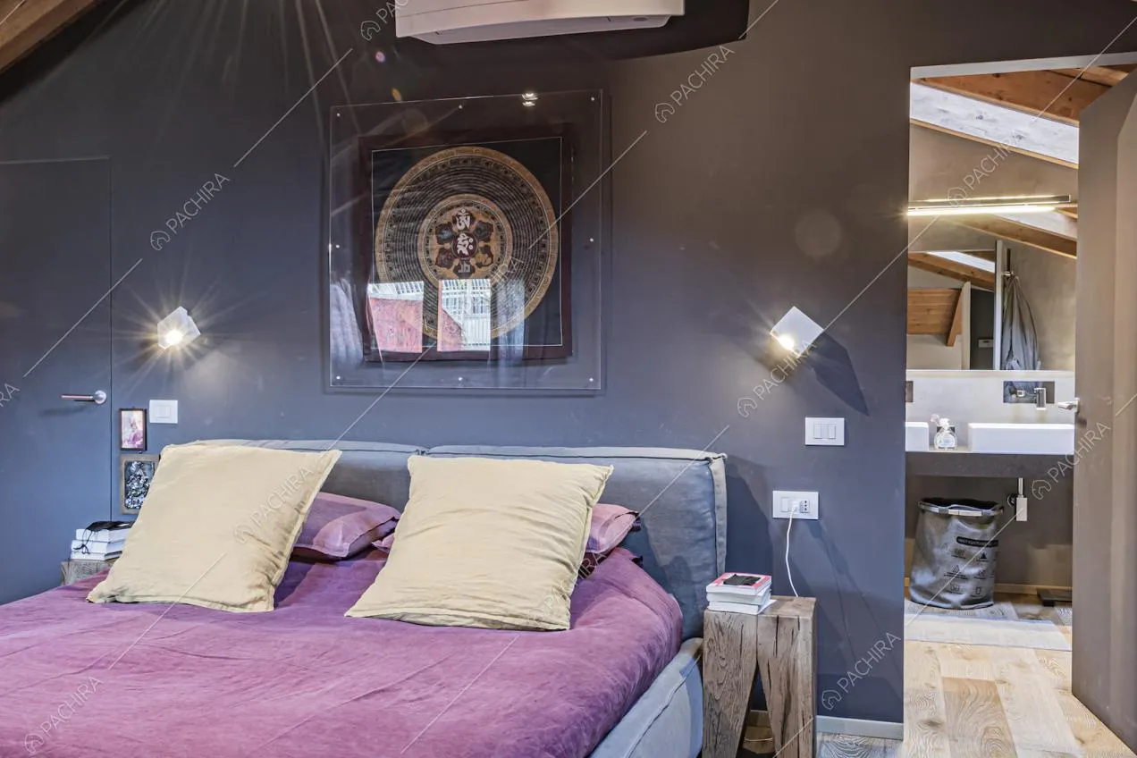 Letto matrimoniale vicino alla parete colorata e scorcio sul bagno
