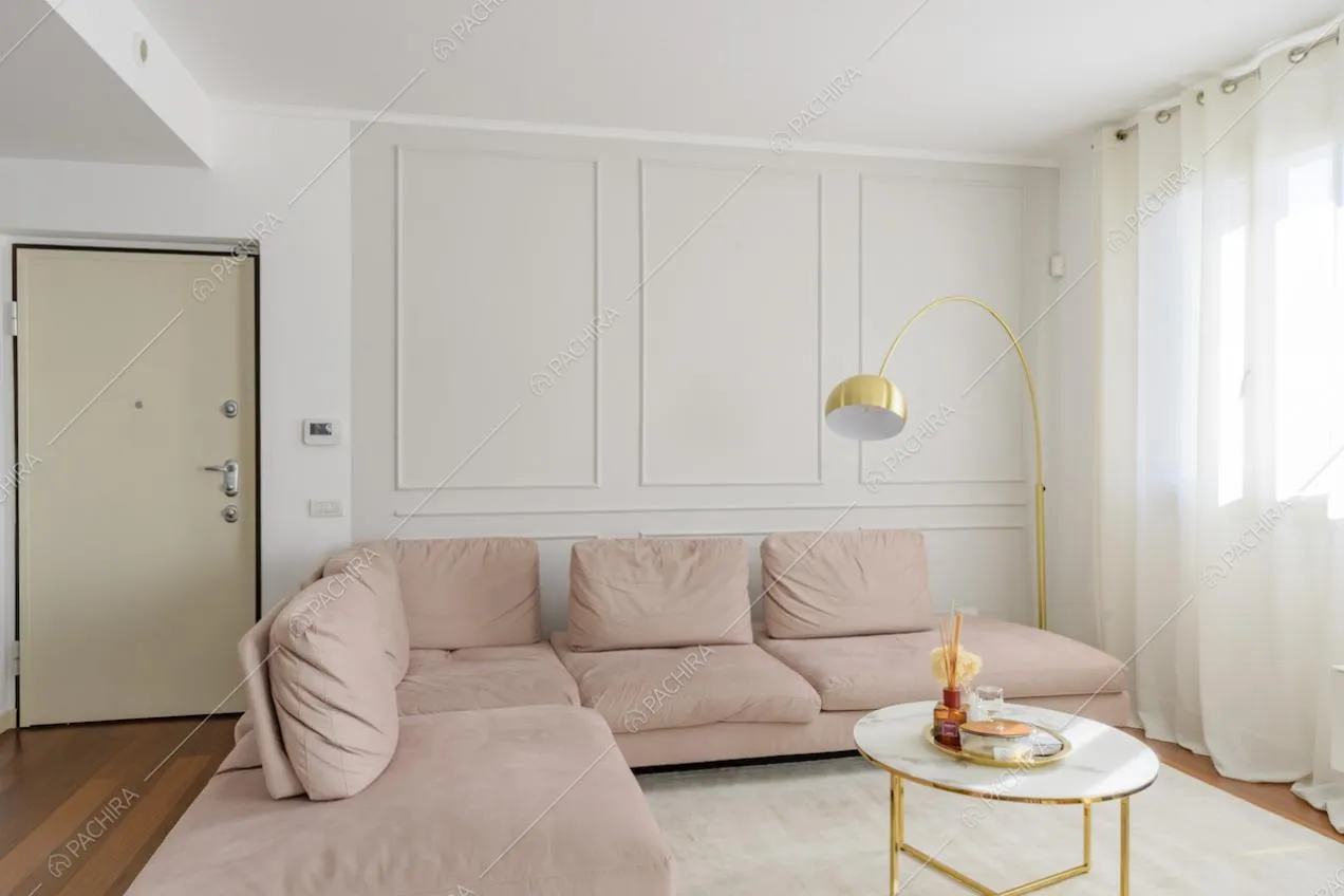 Divano rosa angolare con pavimento in parquet e boiserie alle pareti