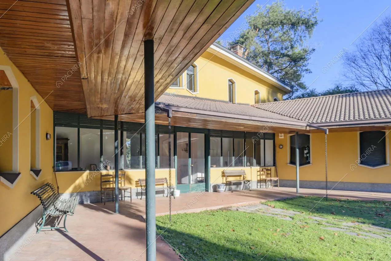 Pergolato con tetto in legno a vista, panchine e accesso alla location con porta-finestra