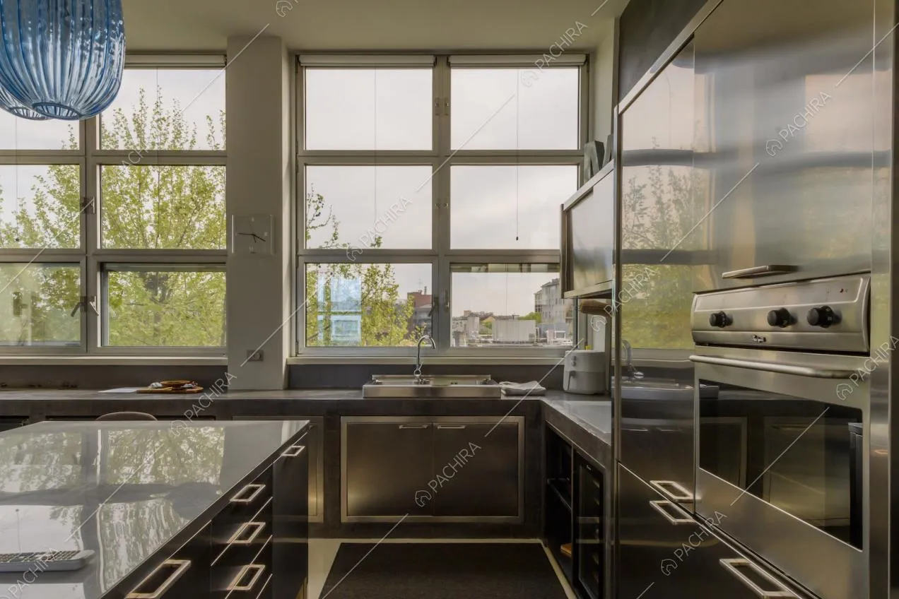 Cucina a isola con elemento in metallo e finestre in stile industriale
