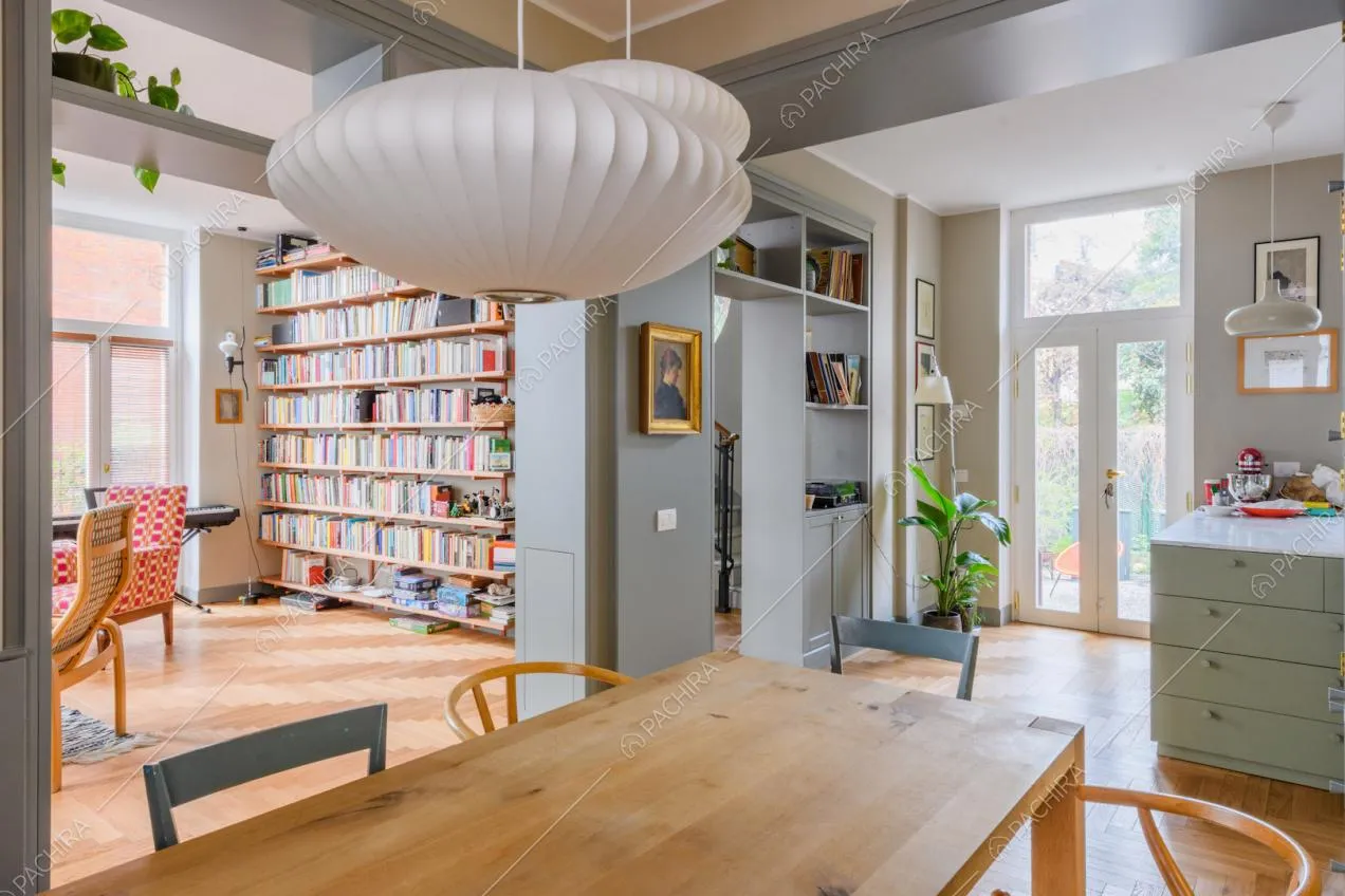 Tavolo da pranzo in legno e vista sulla libreria del salotto e sulla penisola della cucina