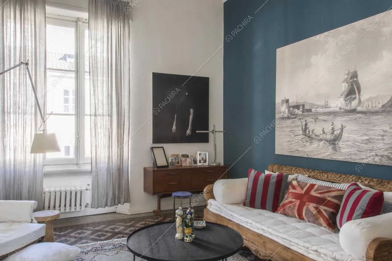Divano in legno intarsiato e quadro in bianco e nero su parete color ottanio