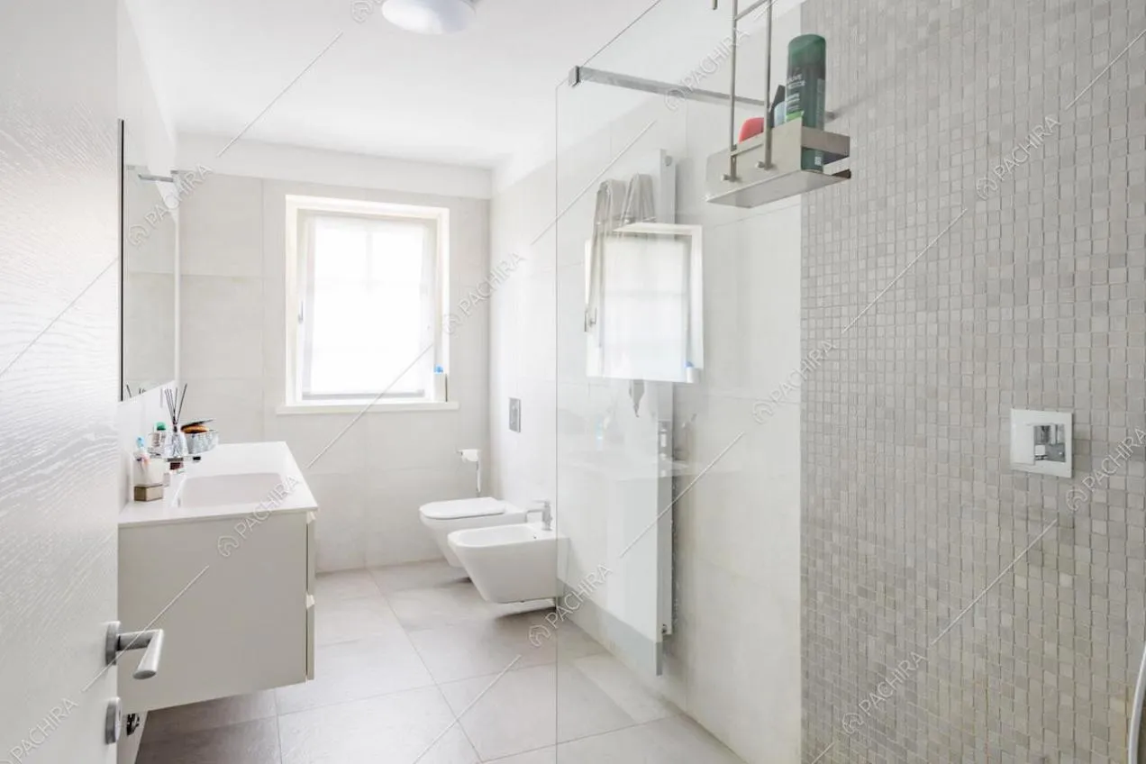 Grande bagno con pareti grigie, box doccia e sanitari sospesi