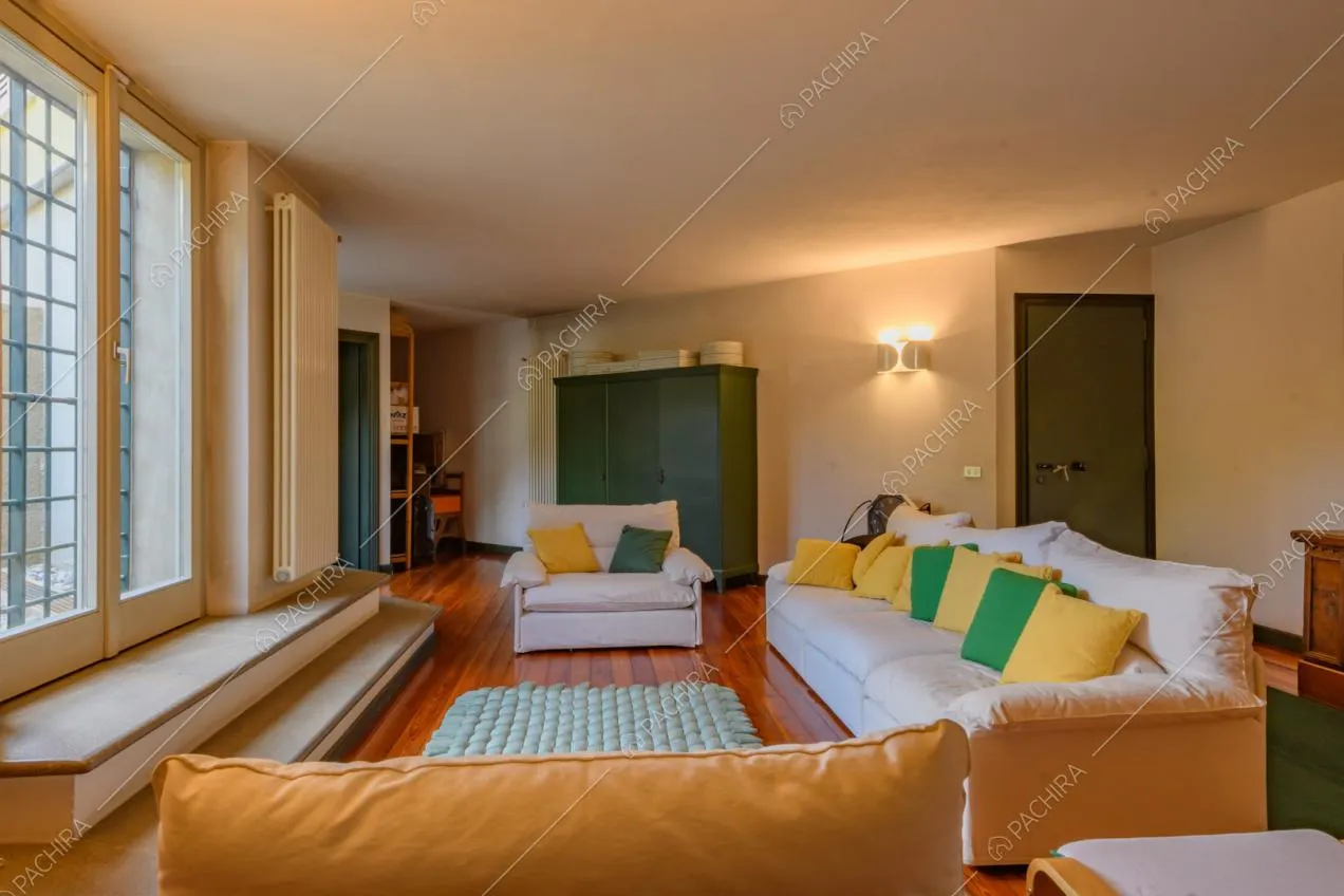 Divani bianchi nella sala con pavimento in parquet e porte-finestre