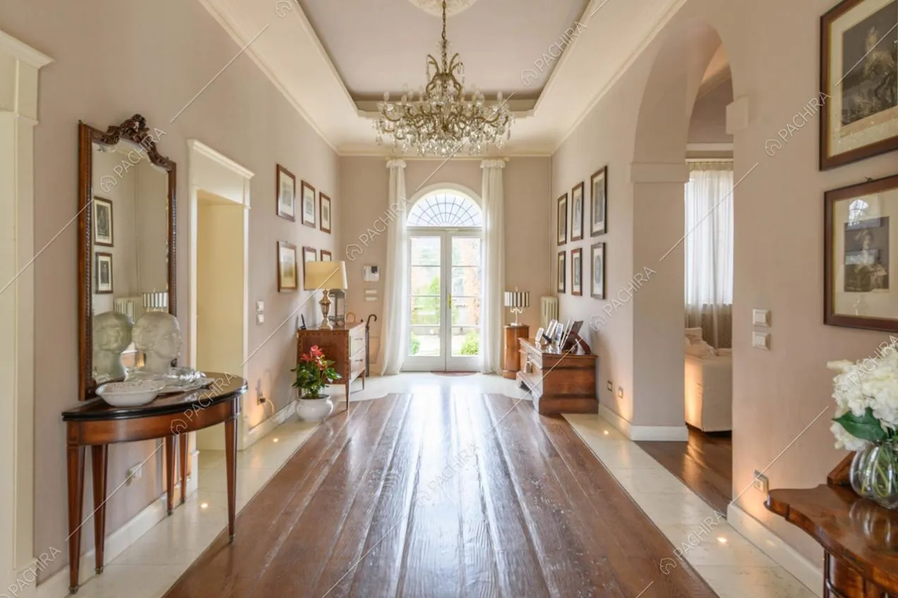 Grande corridoio con pavimento in parquet, lampadario antico e porta-finestra