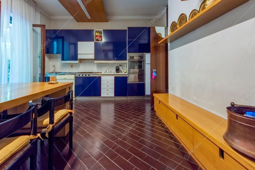 Pavimento in piastrelle marroni e vista sulla cucina blu a parete