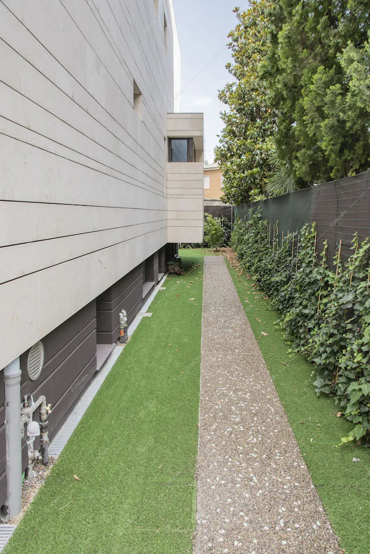 Vialetto nel curato giardino con siepe ed esterni bianchi con righe orizzontali