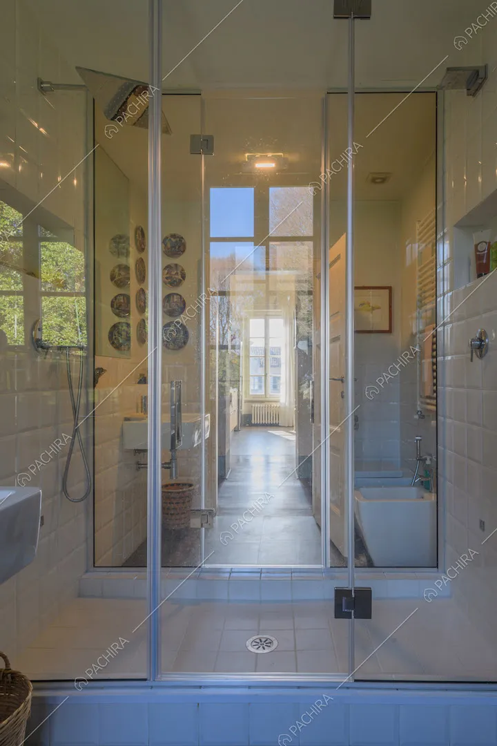 Luminoso bagno con box doccia dal pavimento in piastrelle bianche