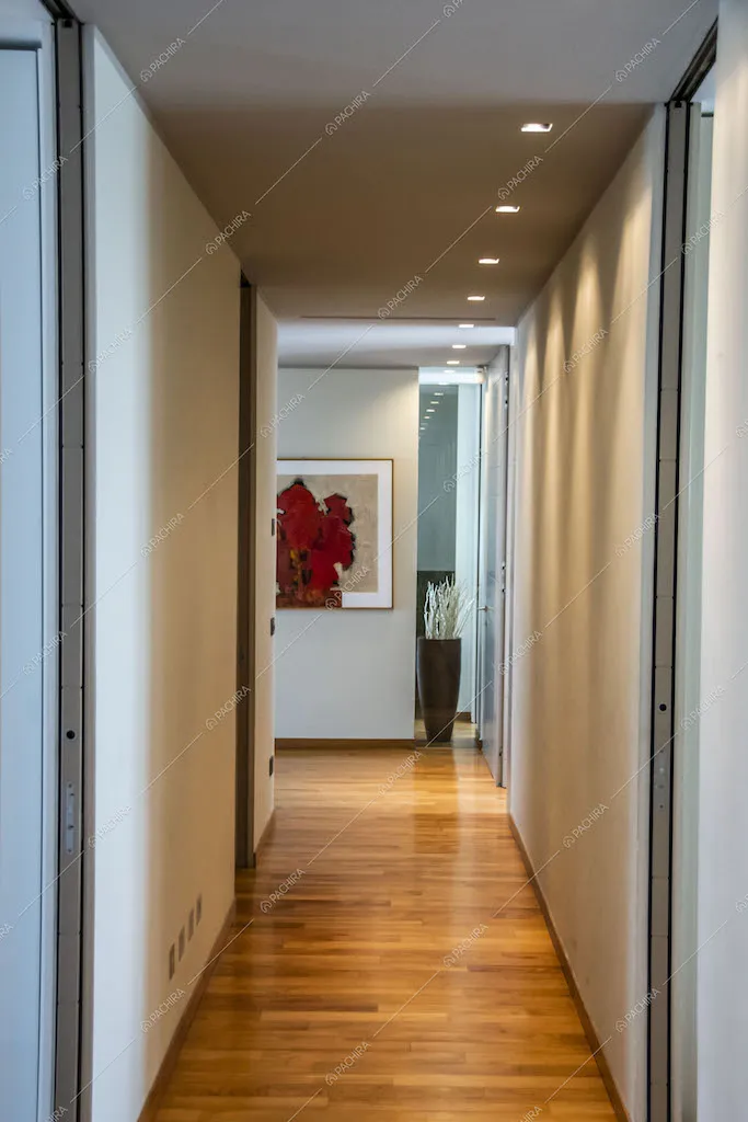 Dal corridoioi con pareti bianche, illuminazione a soffitto e pavimento in parquet accesso al salotto