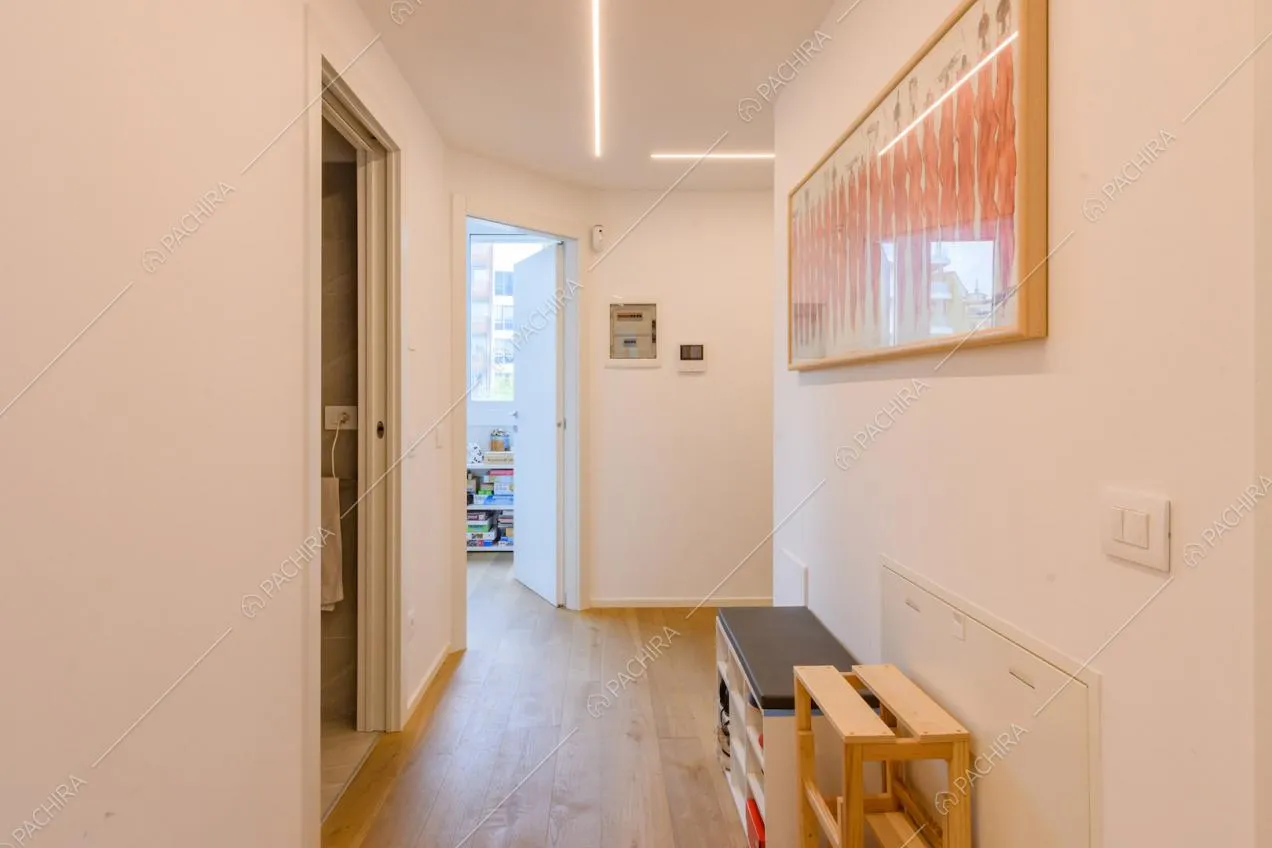 Luminoso corridoio con pavimento in parquet e vista su bagno e camera dei bambini