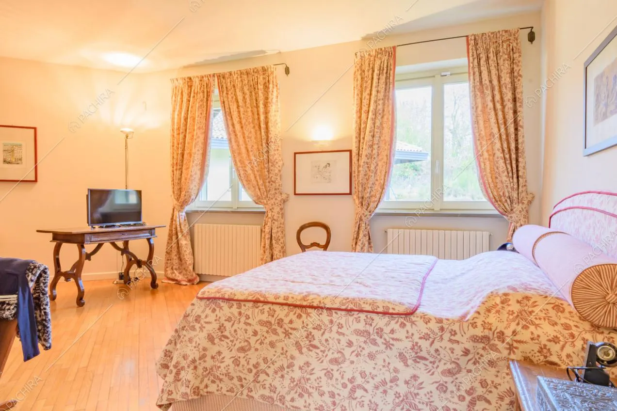 Letto matrimoniale nella camera con pavimento in parquet e vetrate