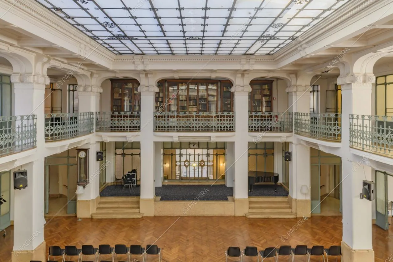 Vista dalla balconata sull'ampio salone con palco, pianoforte e pavimento in parquet