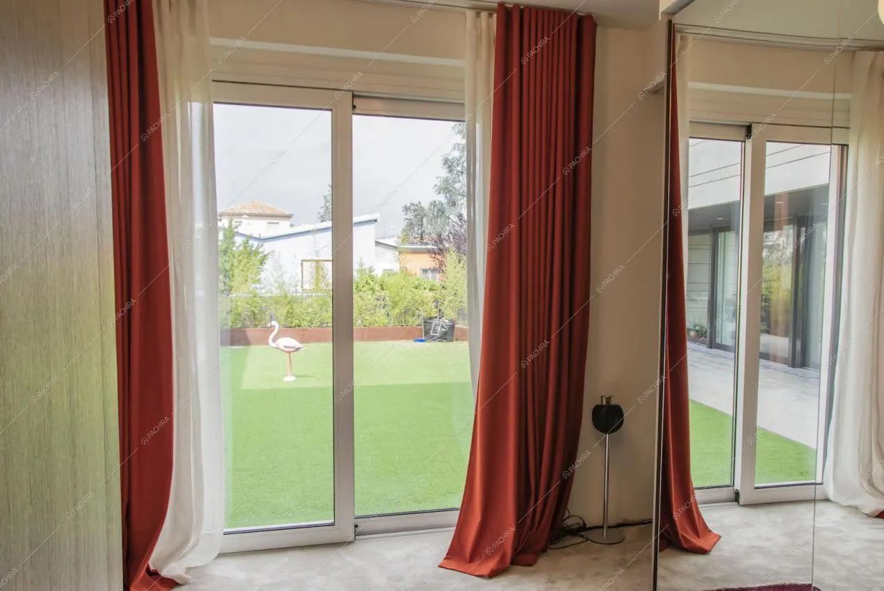 Porte-finestre scorrevoli con tende rosse e vista sul giardino