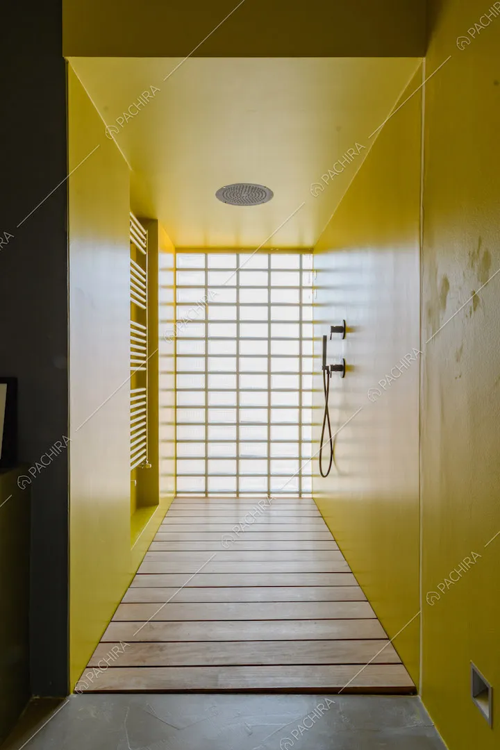 Pareti e soffitto giallo nel bagno con pavimento in travi di legno
