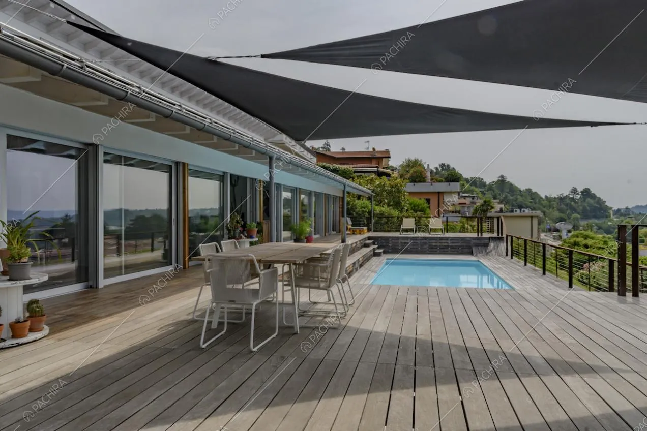 Terrazza con pavimento in parquet da esterni, tavolo da pranzo, vetrate e piscina con vista sul lago
