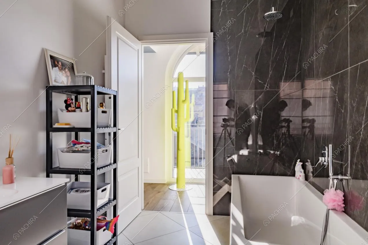 Vasca da bagno, parete in marmo nero e scaffale nel bagno