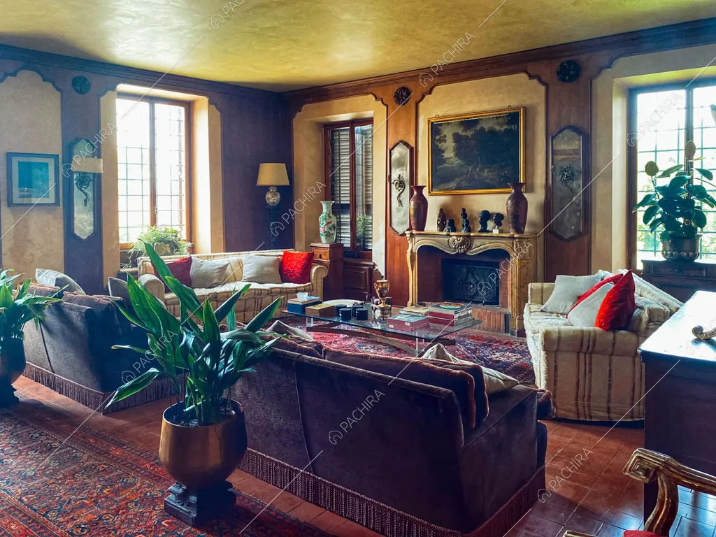 Zona living con boiserie sulle pareti in legno, camino, divanetti e poltrone