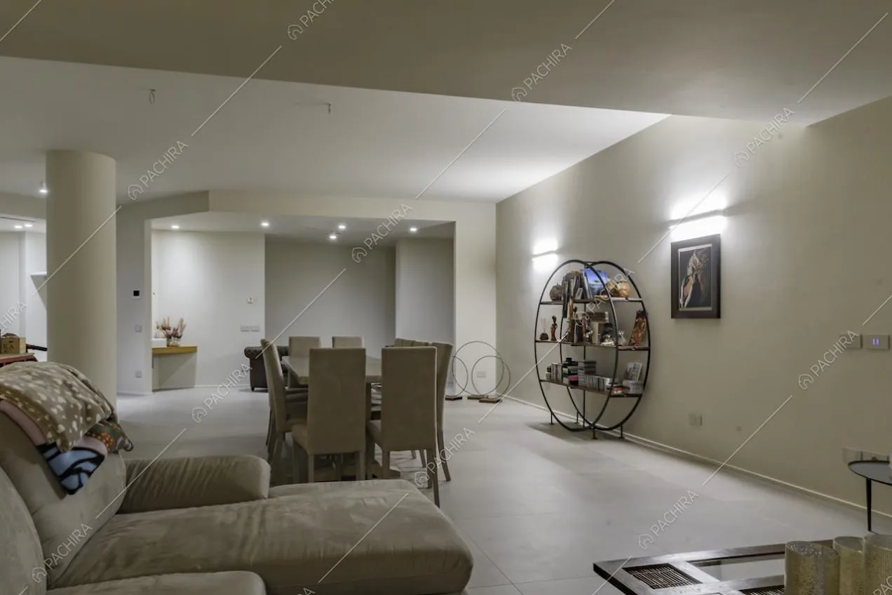 Seminterrato della villa con divano, tavolo da pranzo e particolare libreria a forma di cerchio