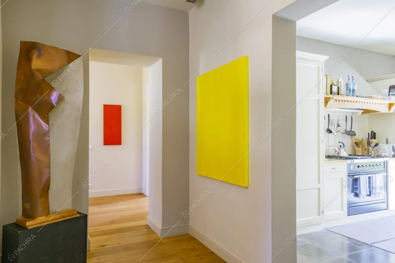 Atrio con pavimento in parquet, opere d’arte e vista sulla cucina