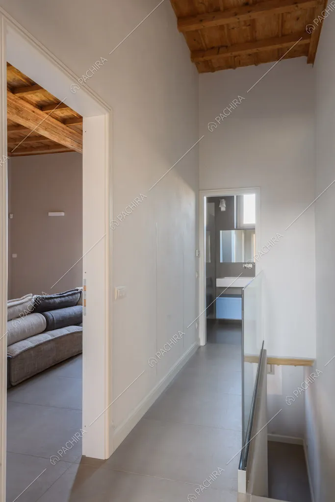 Corridoio dalle pareti bianche con pavimento grigio e soffitto a cassettoni