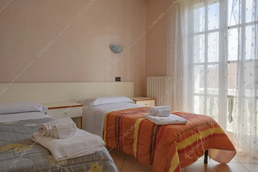 Letti singoli con comodini e parete color rosa chiaro