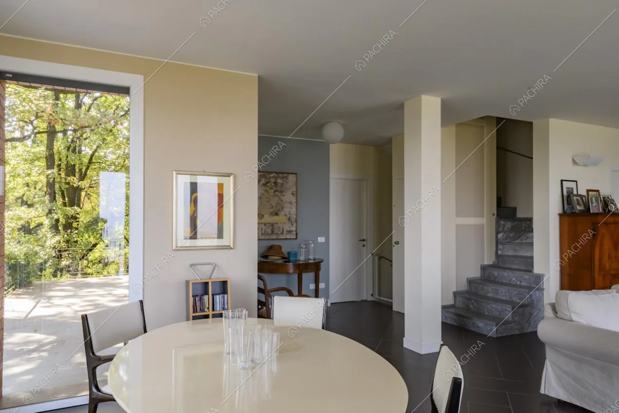 Luminosa sala con ampie vetrate e accesso ai piani superiori